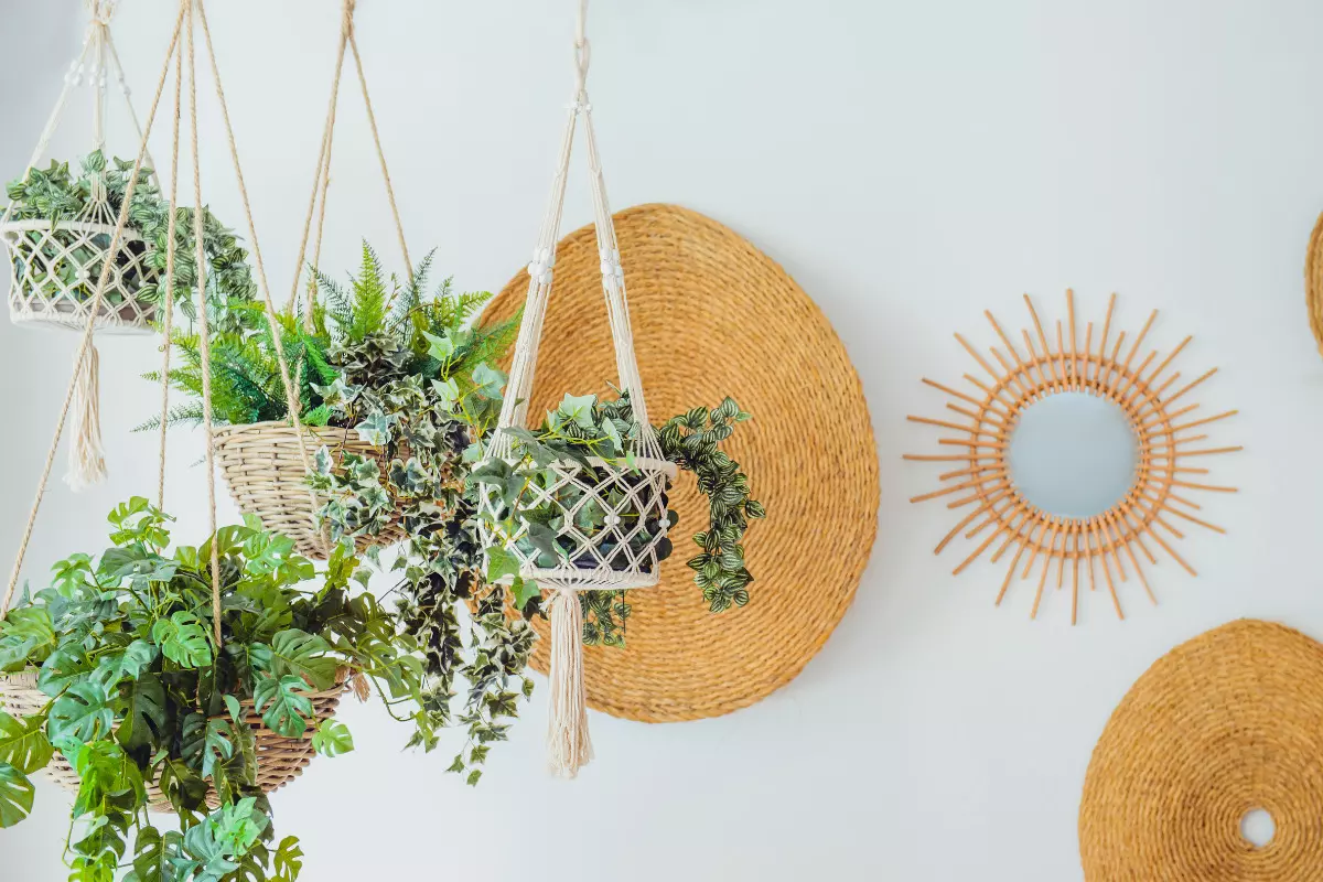 Conheça o estilo Urban Jungle e deixe sua casa aconchegante e mais verde! Plantas penduradas em sala com decoração na parede. Imagem ilustrativa para texto urban jungle.