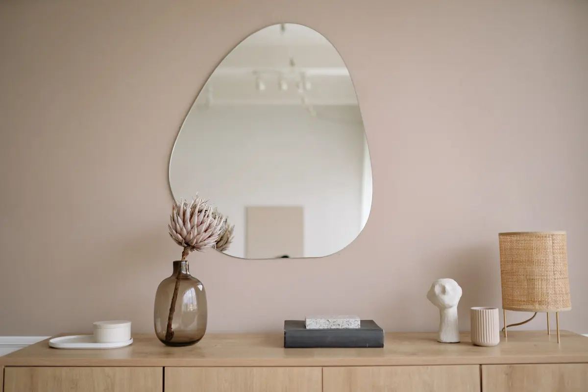 decoração com espelhos na parede da sala em formato diferente, acima de móvel.