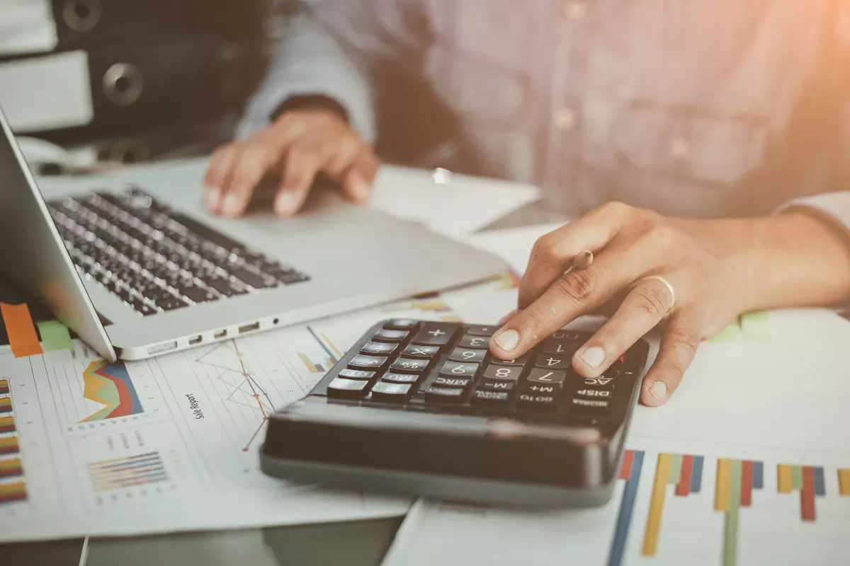 Financiamento ou consórcio: qual a melhor opção para casa própria? Pessoa realizando cálculos sobre financiamento ou consórcio.