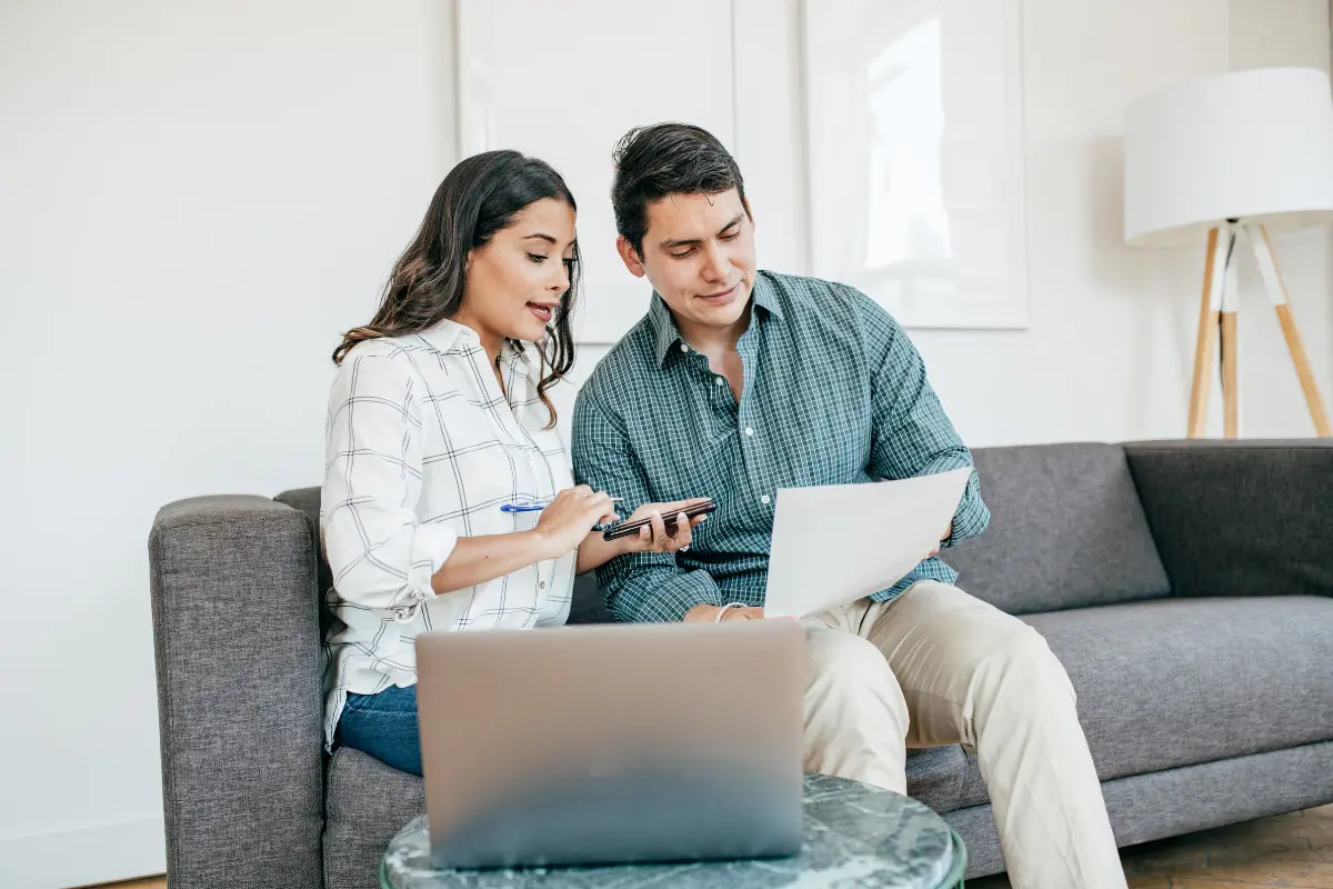 Casal conferindo informações em papéis e computador. Imagem ilustrativa para texto mudar de cidade.
