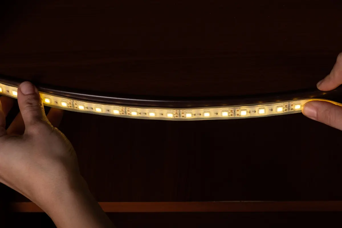 Pessoa aplicando fita de luz de led para quarto.