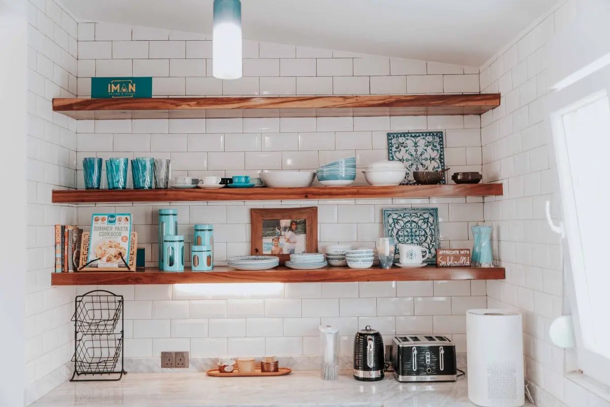 parede de cozinha com prateleiras, quadros e utensílios.
